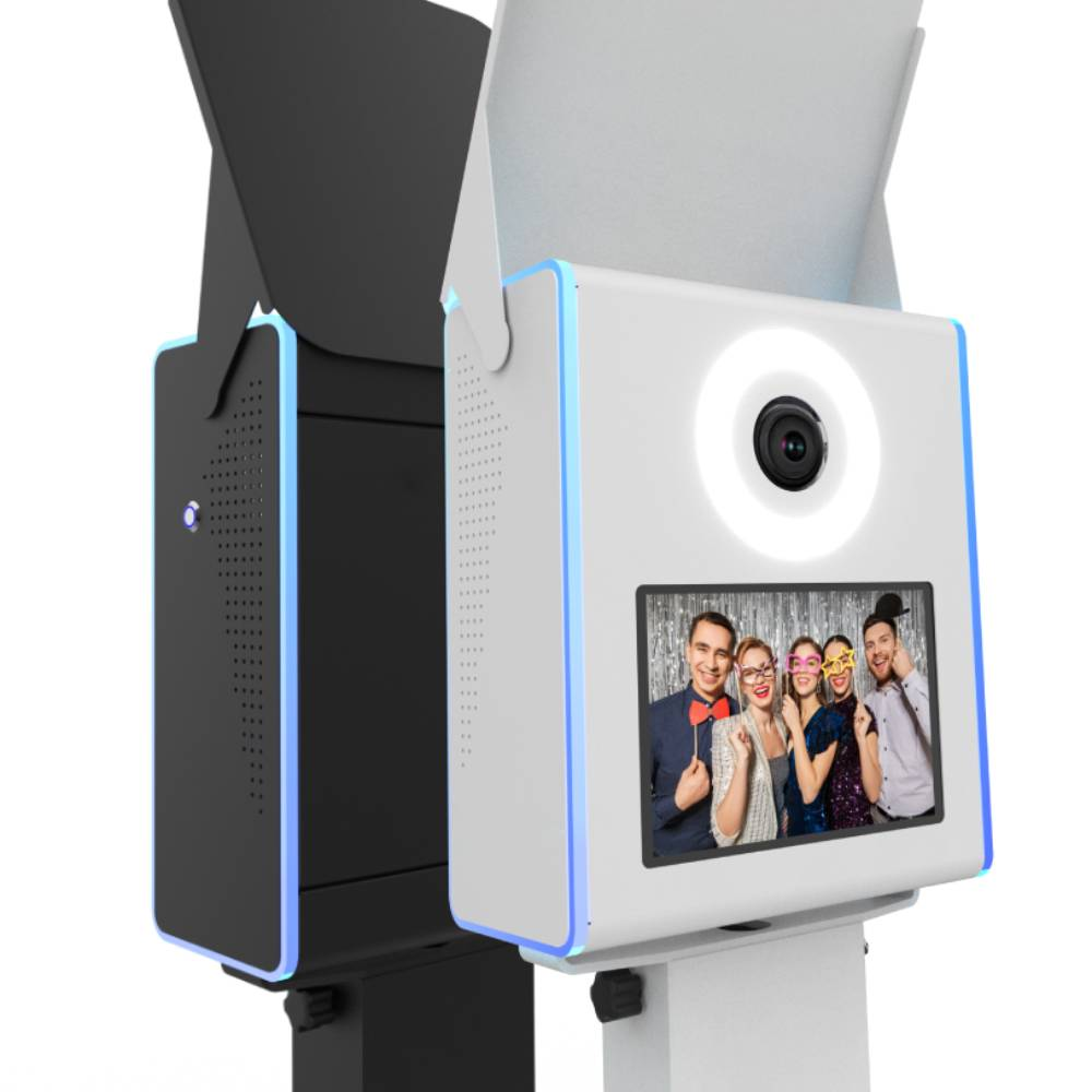 A side-by-side comparison of black and white Marquee photo booth head units, each with a glowing halo ring light, top flash bounce card, and thin blue-lit LED edges.