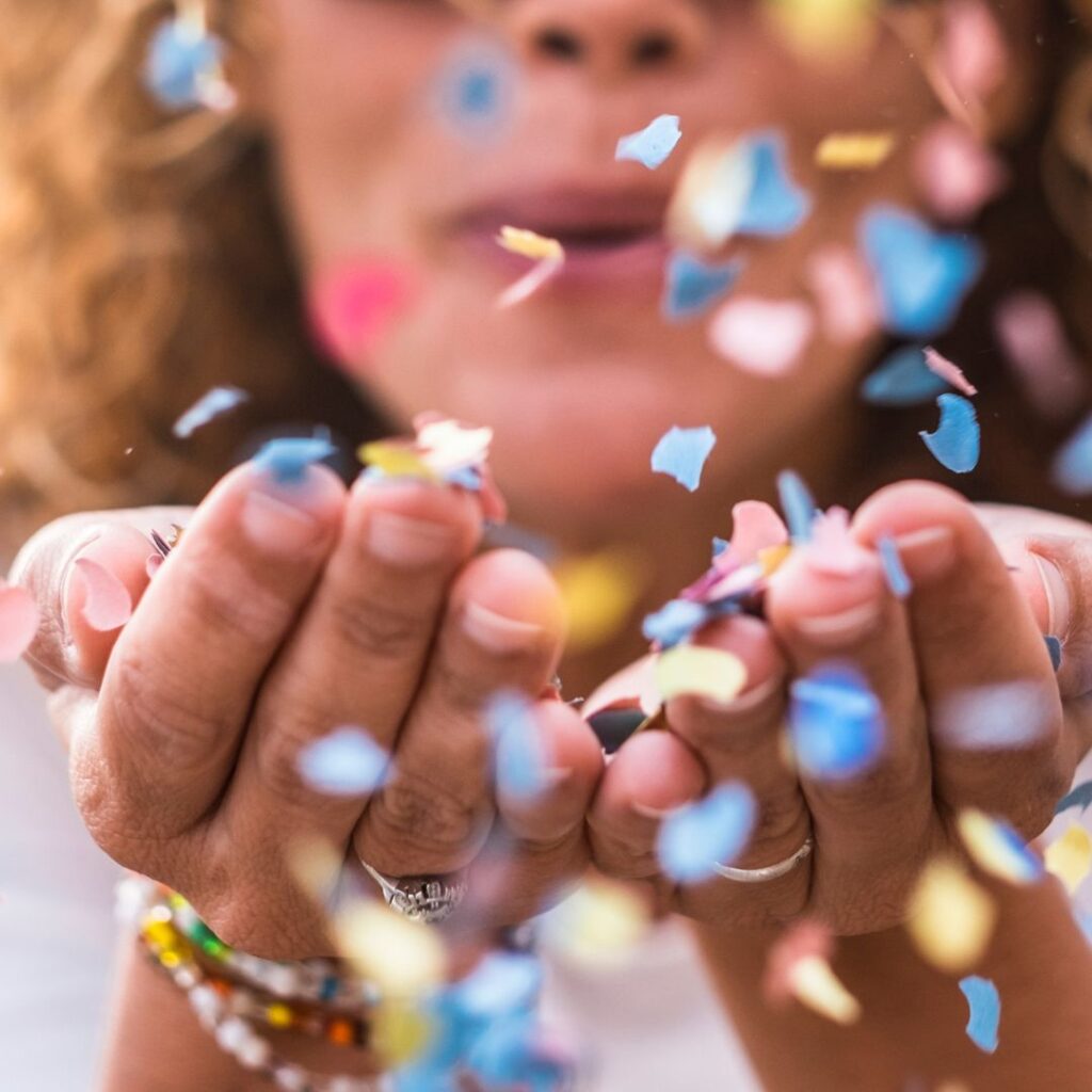 a girl blowing pile of confetti from her hand