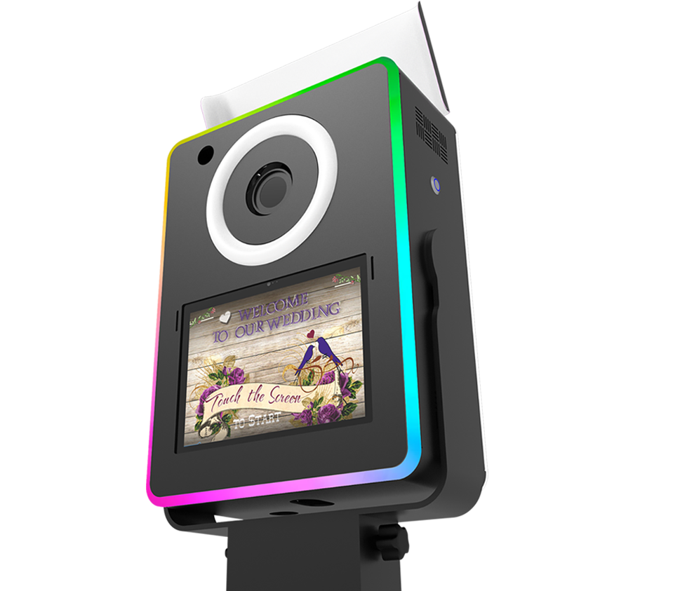 Low-angle view of a black Lumia photo booth head unit with a top flash bounce card, glowing RGB chasing LED edges, and a halo ring light.